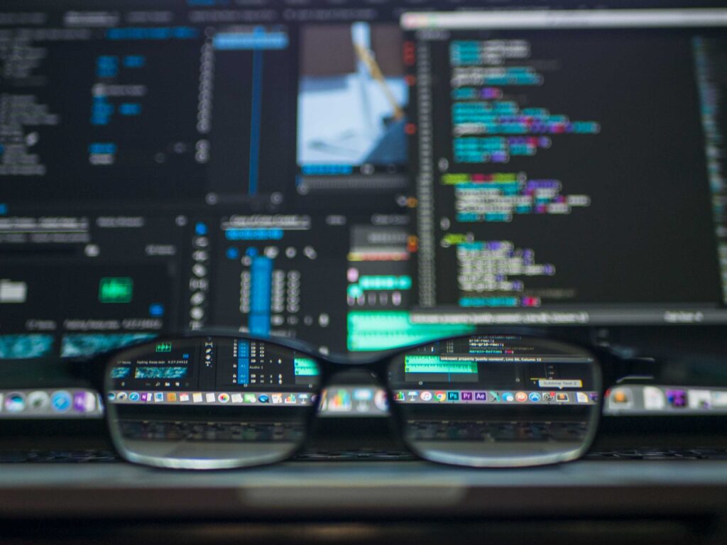 Glasses in front of computers showing code.